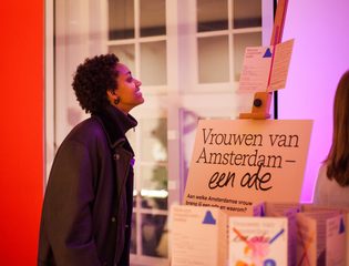 Persoon bekijkt bord met tekst Vrouwen van Amsterdam - een ode.