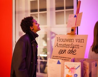 Persoon bekijkt bord met tekst Vrouwen van Amsterdam - een ode.