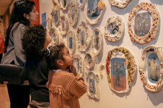 Twee kinderen en een vrouw kijken naar kunst aan de muur