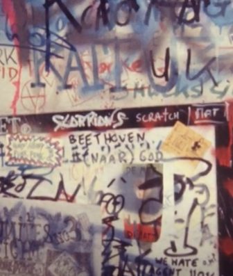 Muur in het Zebrahuis bedekt met graffiti, stickers en handgeschreven teksten.