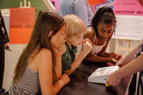 Drie kinderen die naar een spel verpakking kijken