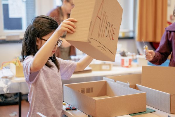 Kind is aan het werk met kartonnen dozen.