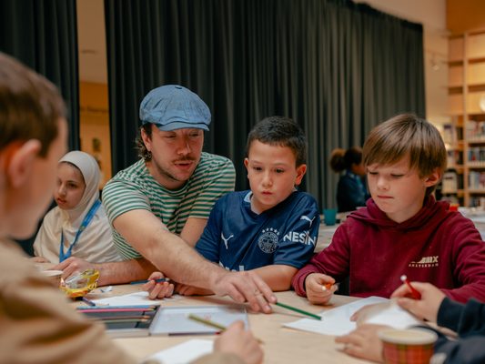Kinderen krijgen uitleg van kunstenaar.