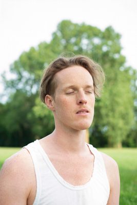 Kunstenaar Venus Jasper staat in een grasveld met ogen dicht.