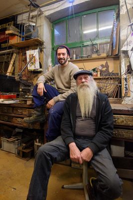 Portret van Meister en Scauso in atelier, zittend op stoel en werkbank.